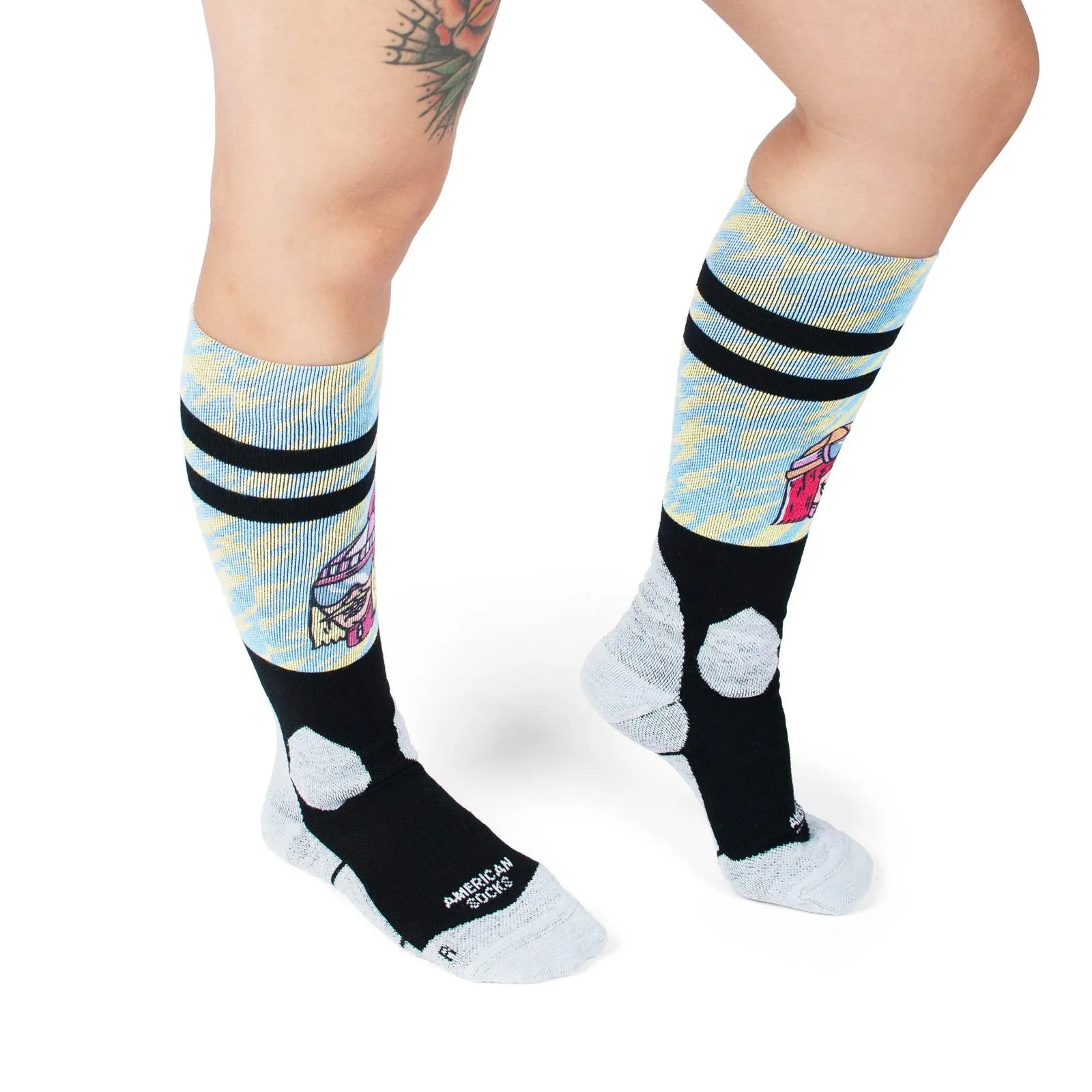 Legs with patterned Slope Dope Snow Socks, black with American Socks logo. Pattern with beach motif.