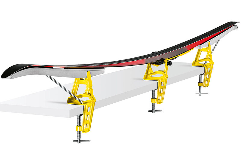 Ski de fond tendu dans un système de serrage de ski jaune en trois parties sur une surface blanche.