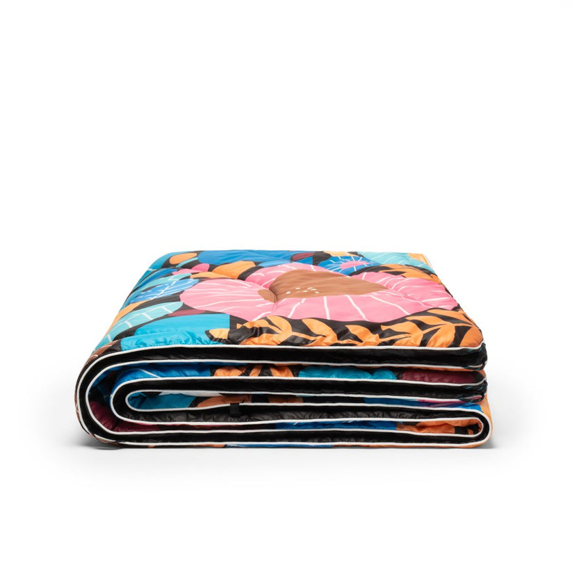 Zusammengefaltete Rumpl Original Puffy Blanket mit Night Garden Muster, Blumen in rosa, blau und braun Tönen.