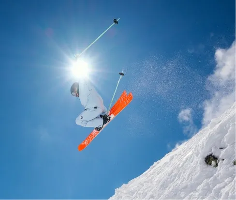 Sciatore con gli sci Black Crows Draco Freebird che salta davanti al cielo blu e alla neve.