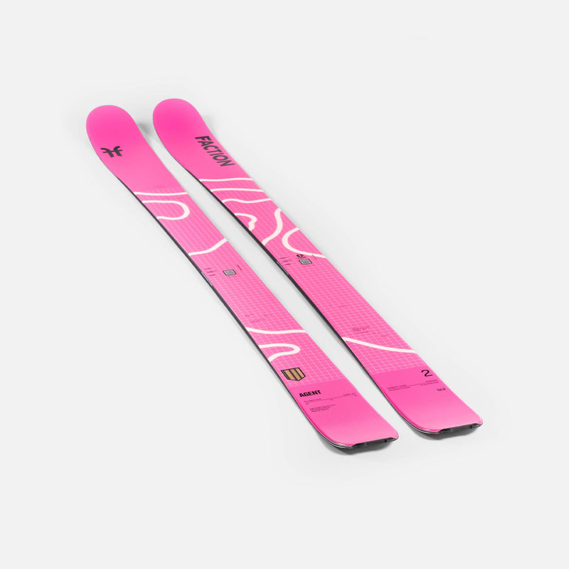 Zwei pinke Ski mit weißen Akzenten liegen diagonal auf einem weißen Hintergrund. Die Ski sind mit "Faction" und "Agent" beschriftet.
