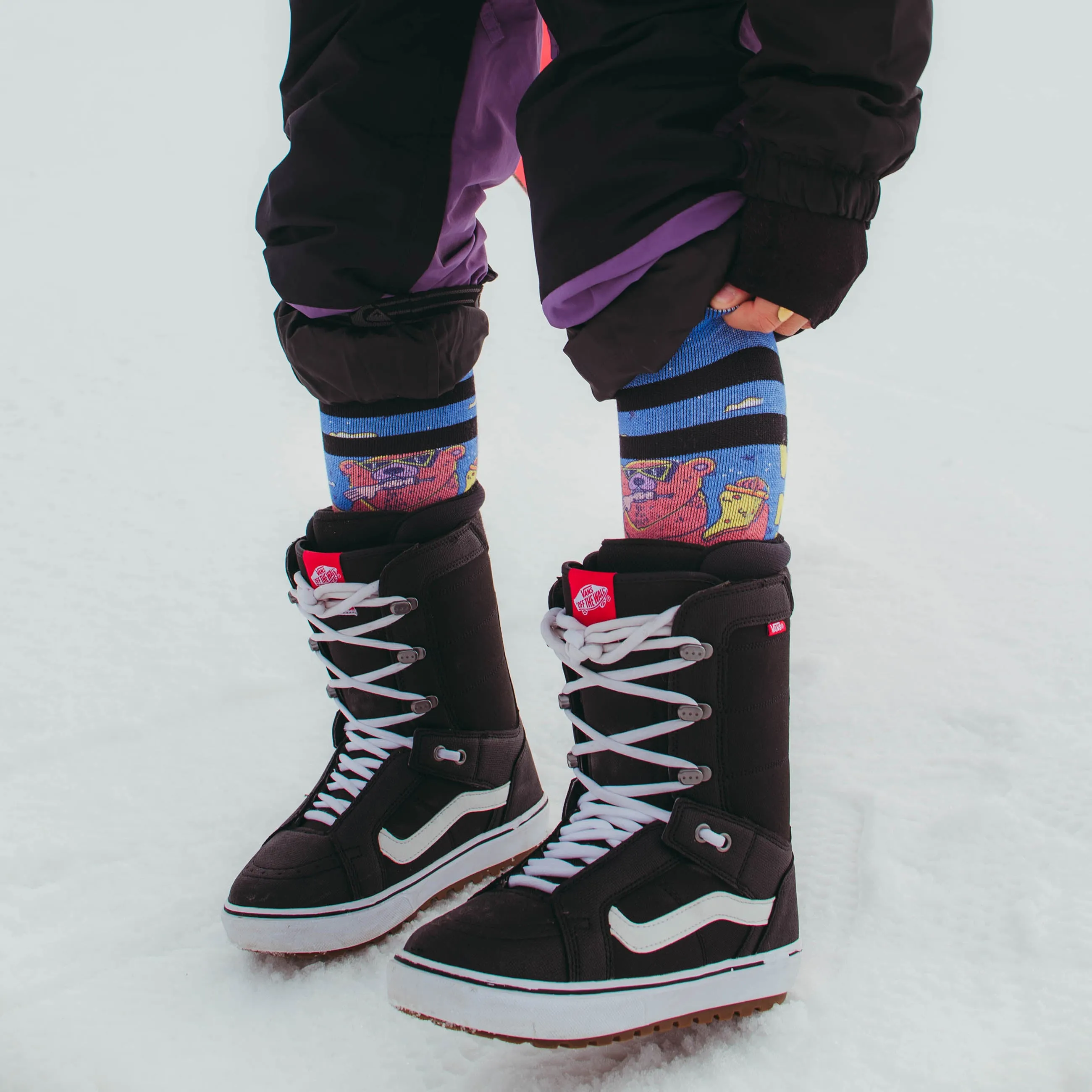 Persona con scarponi da snowboard e calzini Wild Nature sulla neve. Calzini con motivo di orso.