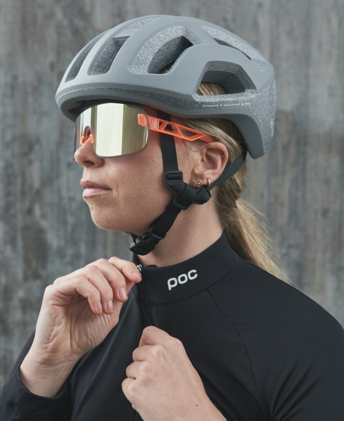 Frau mit Elicit Sonnenbrille Frau mit Helm und Elicit Fluorescent Orange Sonnenbrille mit Gold Mirror Glas.