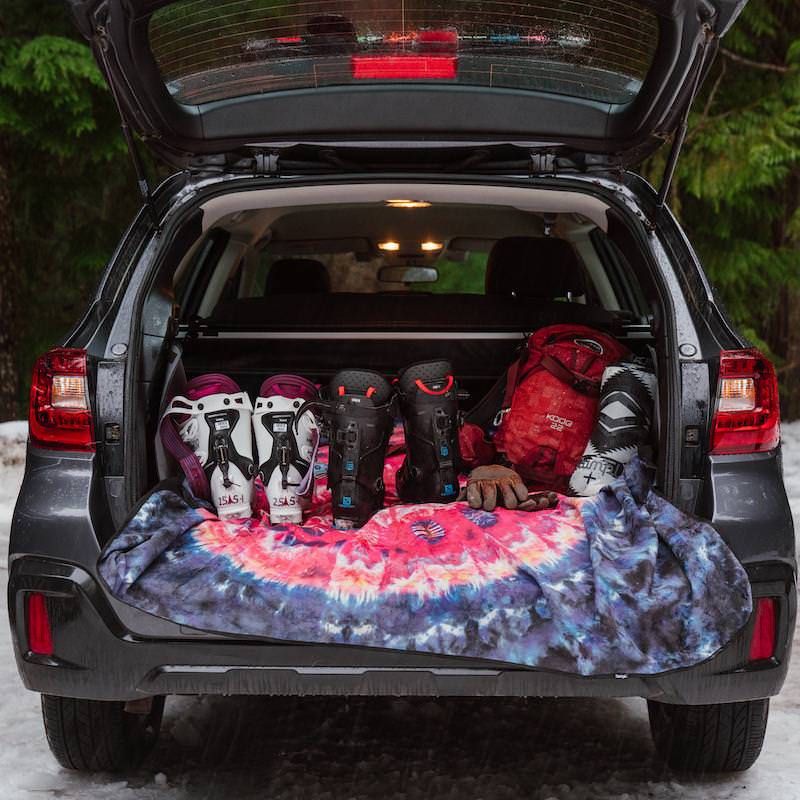 Offener Kofferraum mit Skischuhen, Rucksack und Cosmic Soul Stash Matte.