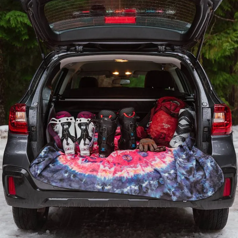 Offener Kofferraum mit Skischuhen, Rucksack und Cosmic Soul Stash Matte.