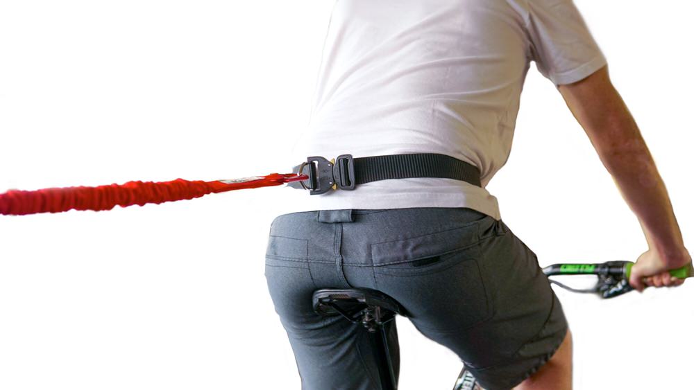 Tow-Whee Hüftgurt Radfahrer mit Tow-Whee Hüftgurt und roter Zugschnur, befestigt am schwarzen Nylon-Gurtband.