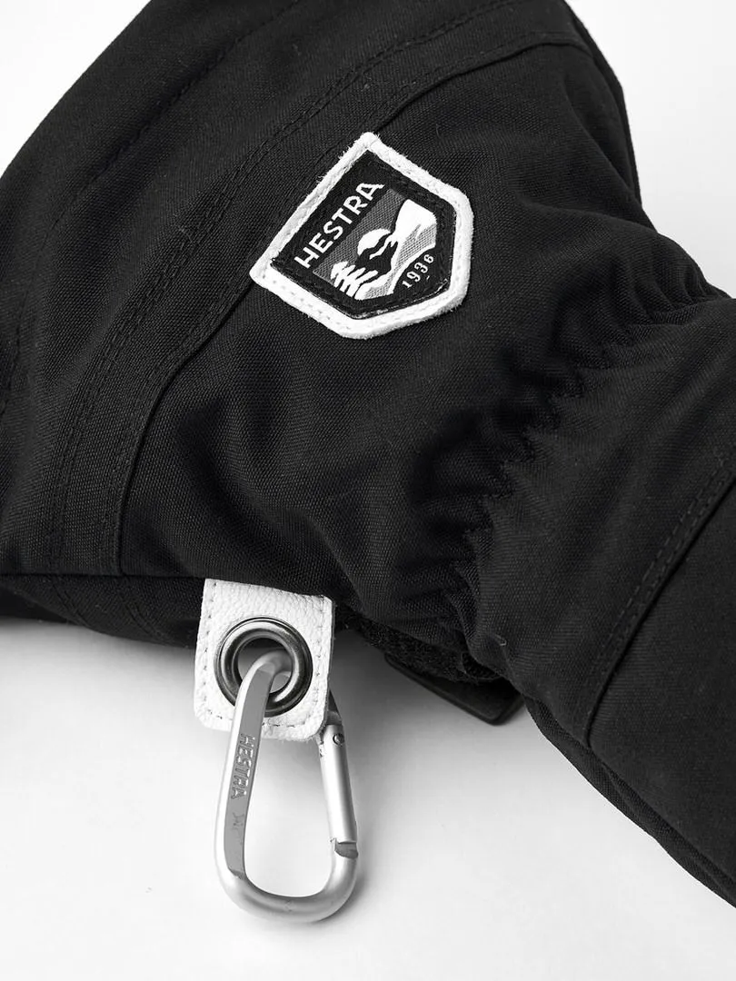 Détail d'un gant noir avec le logo Hestra, une dragonne blanche et un mousqueton.