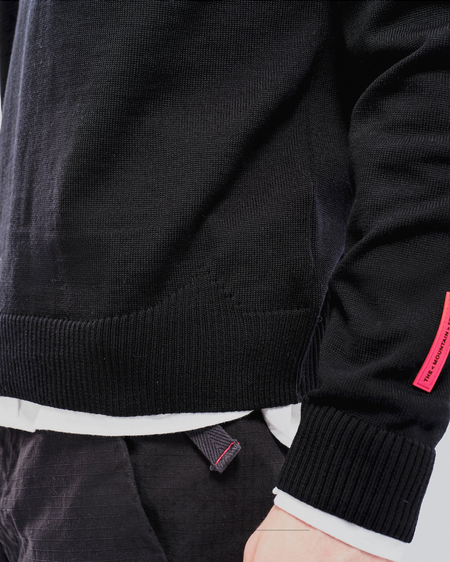 Black K-3 ski sweater Close-up of a black K-3 ski sweater made of merino wool with a round neckline and red label.