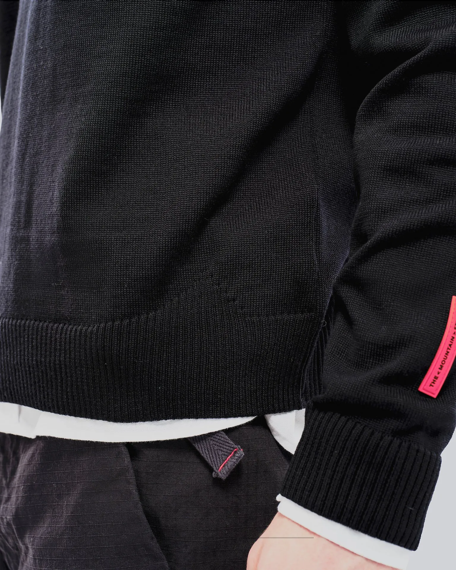 Nahaufnahme eines schwarzen K-3 Ski Pullovers aus Merinowolle mit Rundhalsausschnitt und rotem Etikett.