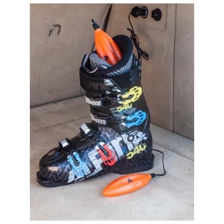 Schuh mit Alpenheat Schuhtrockner. Orangefarbener Trockner im Schuh und davor. Kabelanschluss im Hintergrund.