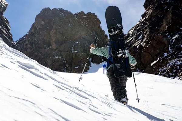 Person mit Splitboard und Jones Talon Pro Skistöcken auf Skitour im Schnee.