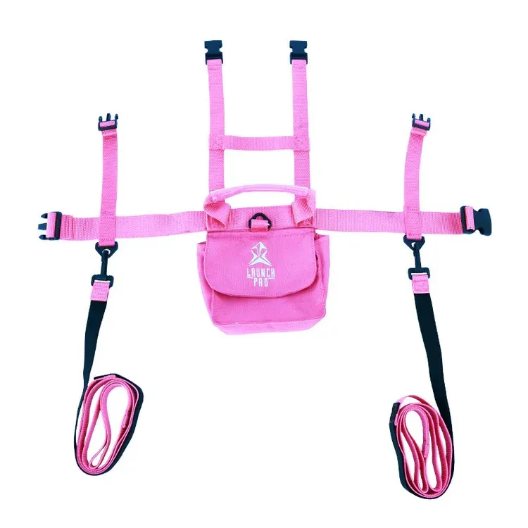 Pink toddler ski harness with leashes: adjustable shoulder straps and padded center section featuring the “LAUNCH PRO” logo and a carrying handle. Two removable black-and-pink leashes on the sides, rolled up at the bottom. Multiple buckles.