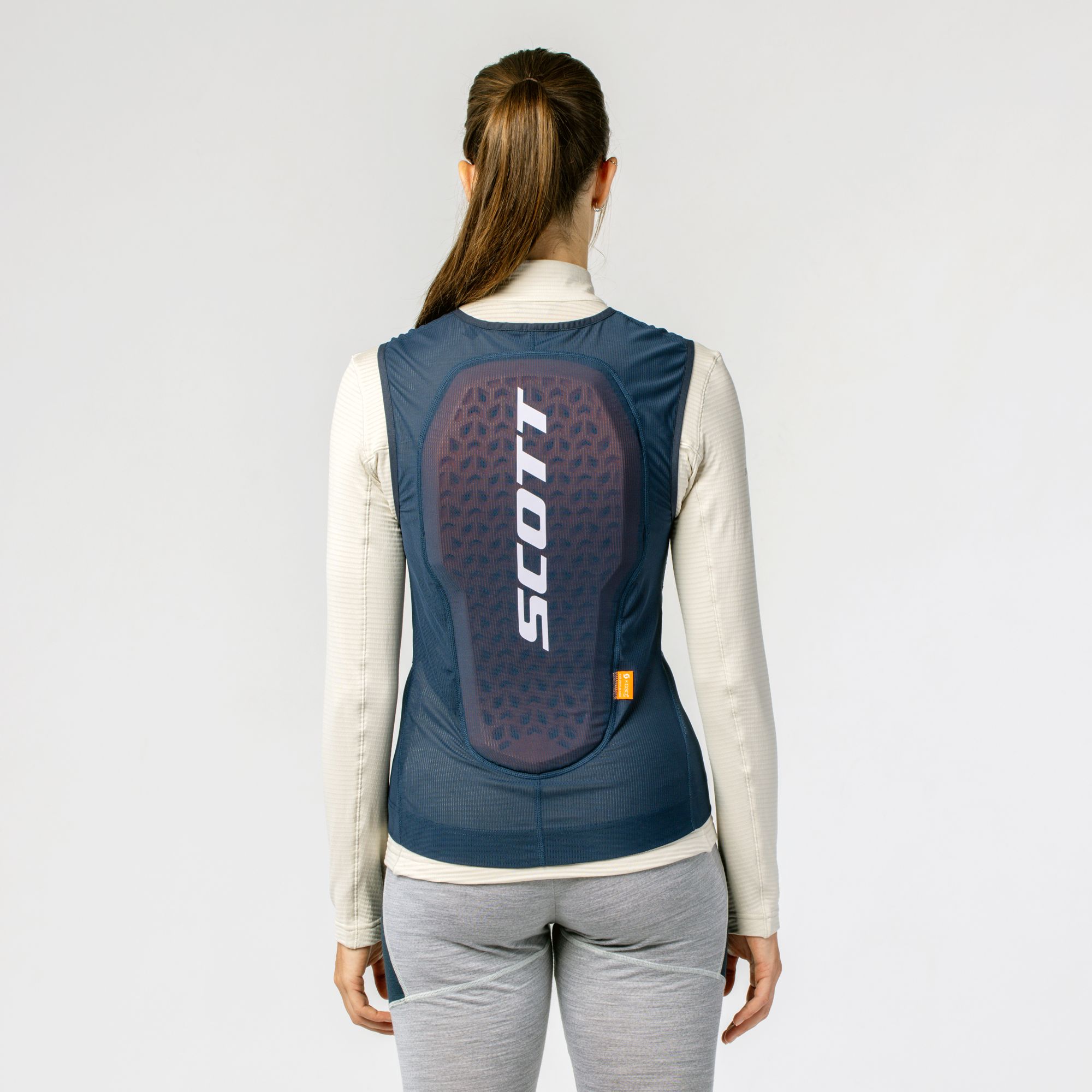 Scott Airflow Weste Rückenansicht einer Frau mit Scott Airflow Weste in Blau/Weiß. Die Weste hat einen Rückenschutz mit großem Scott-Logo.