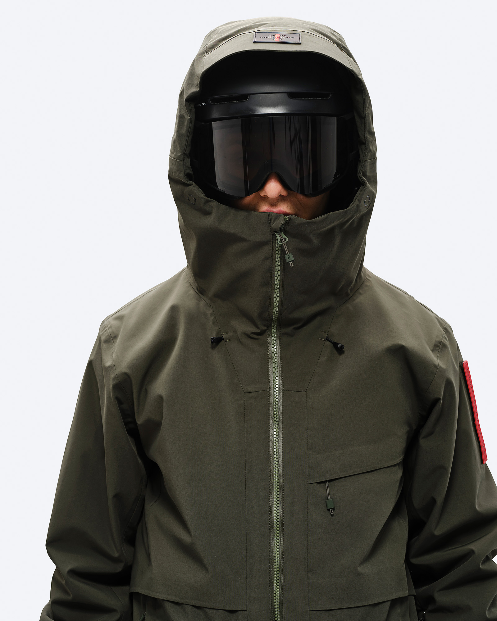 Veste de ski "Forest Green Personne portant une veste de ski "Forest Green" avec capuche et lunettes de ski. Vue de face jusqu'aux hanches.