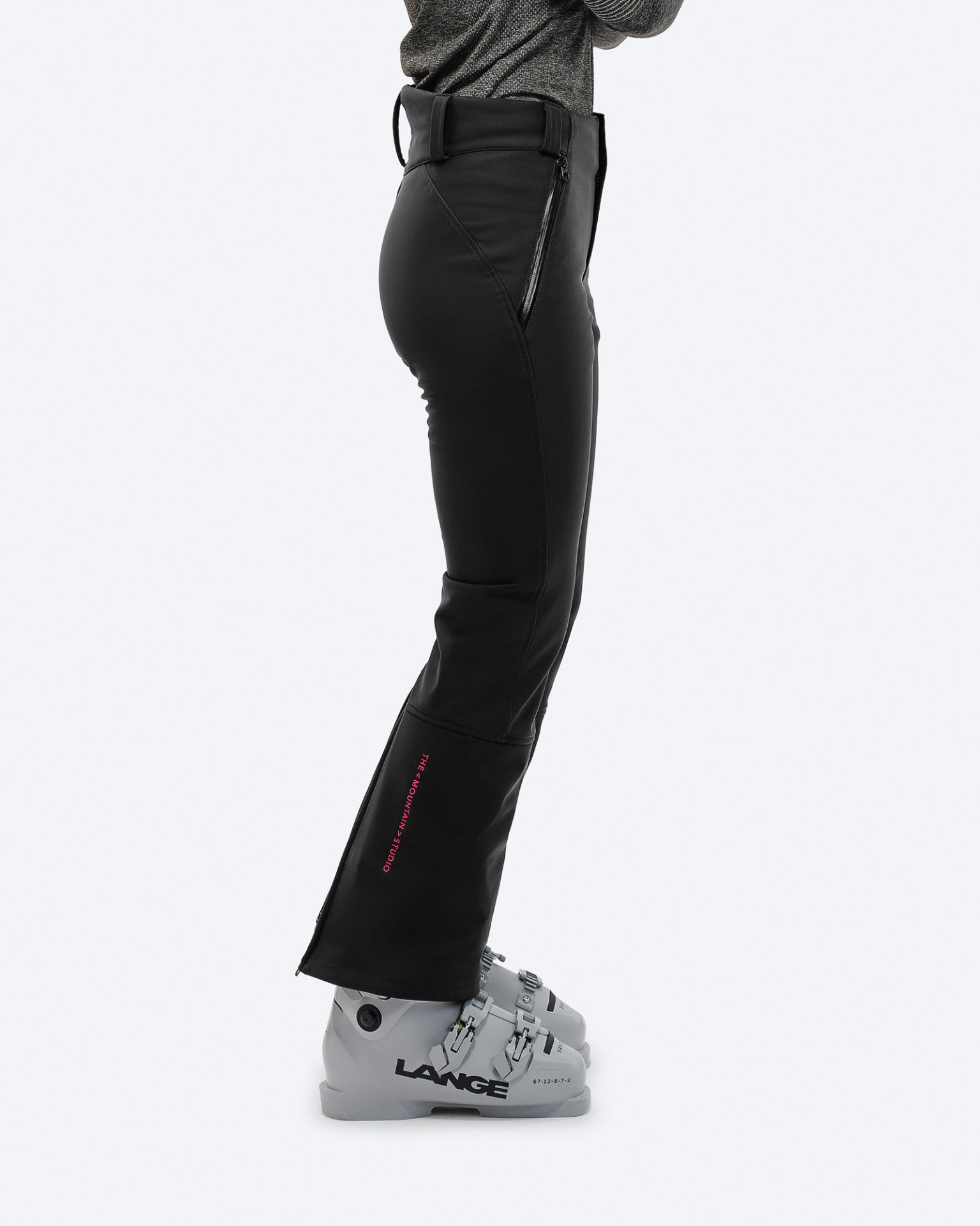 Black ski pants A person in black P-4 W 2L stretch ski pants with ski boots, side view.