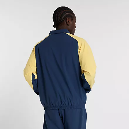 New Balance Track Jacket Rückansicht einer New Balance In Game Woven Track Jacket in Navy mit gelben Ärmeln an einem Mann.