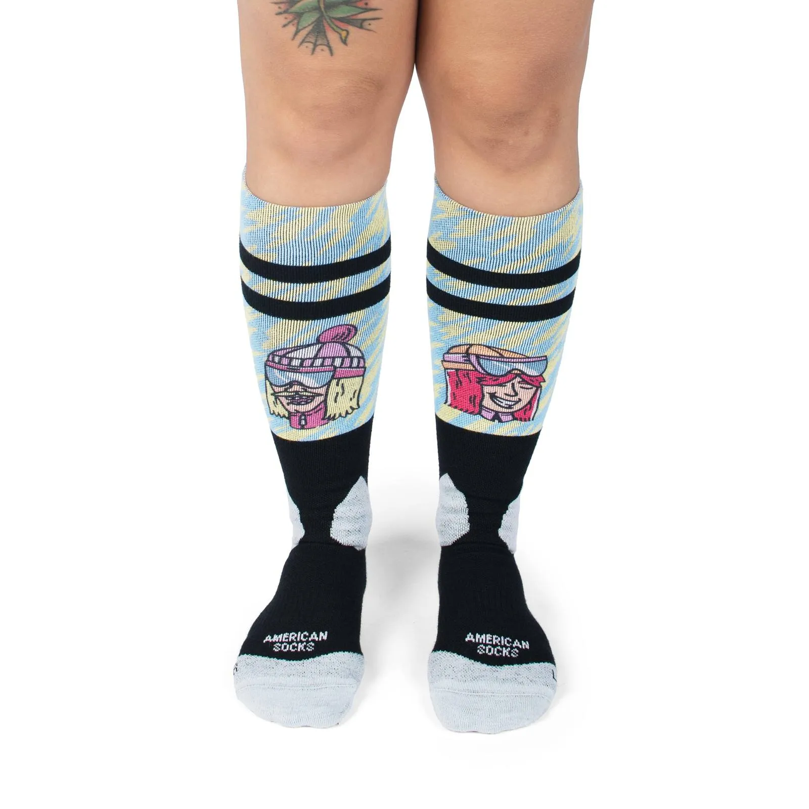 Legs in slope dope snow socks with ski motifs, blue patterns and black stripes. "American Socks" lettering visible.