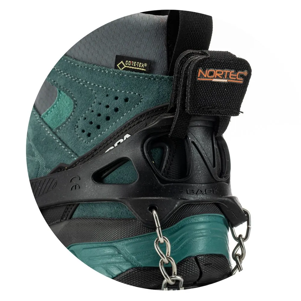 Detailaufnahme: Trekking-Steigeisen an Bergschuh befestigt. Schwarzes Elastomer mit Kette und Stahlplatten an grün-grauem Schuh.