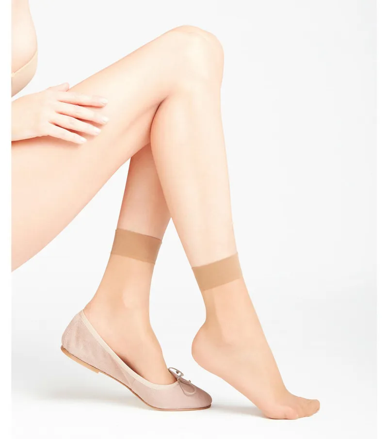 Beine mit transparenten, hellbraunen 15 DEN Damen Söckchen und Ballerina-Schuh.
