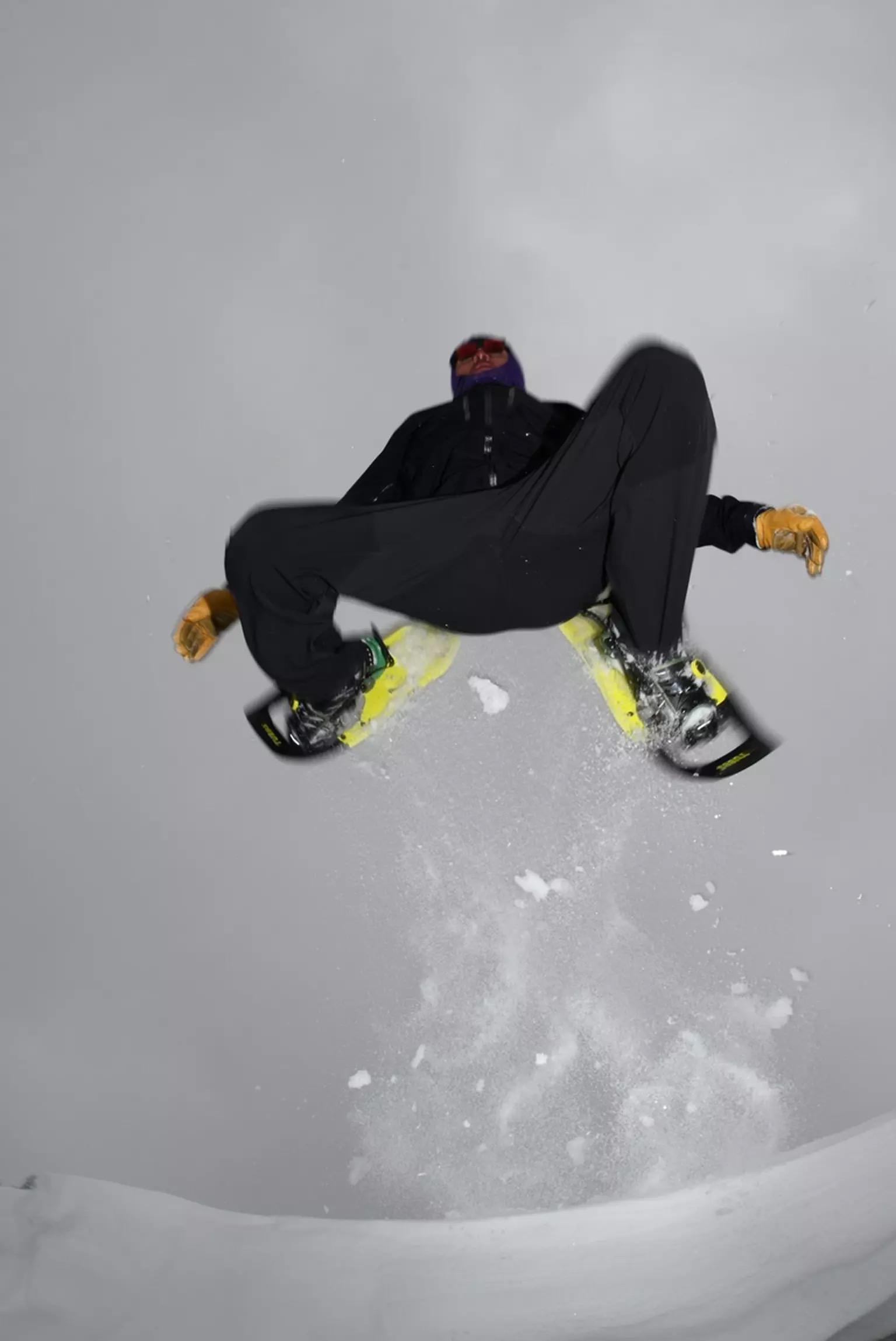 Homme sur des raquettes à neige jaunes Un homme saute sur une surface enneigée sur des raquettes à neige Tubbs VRT 29 jaunes.