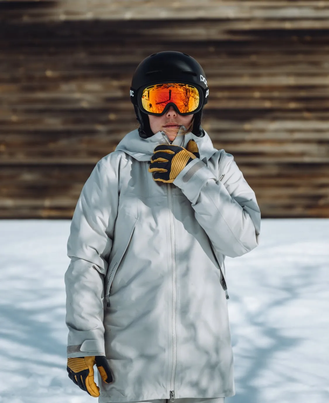 Persona con casco da sci Fornix Mips in nero e occhiali di colore arancione, abbigliamento invernale e guanti sulla neve.