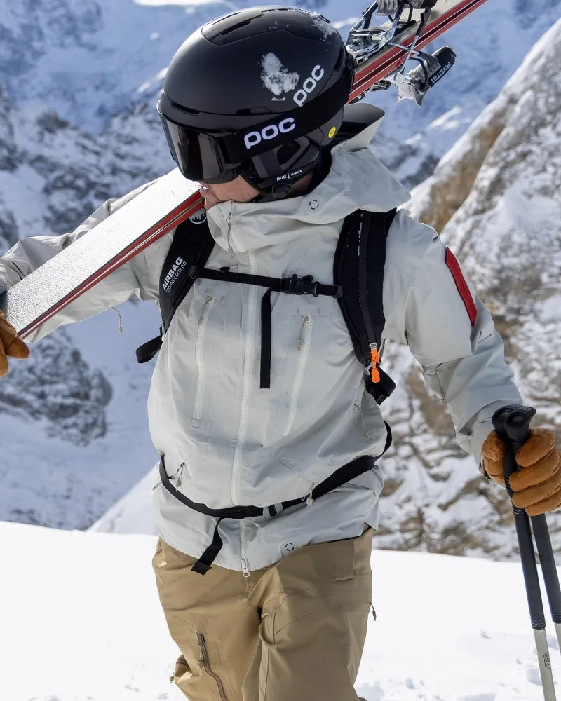 Skier with Z-2 HD GORE-TEX Pro 3L Shell Jacket in Castle Wall, with skis and poles in a snowy mountain landscape.