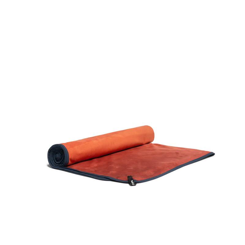 Ein orangefarbenes, aufgerolltes Rumpl Shammy Towel mit dunkelblauem Saum.