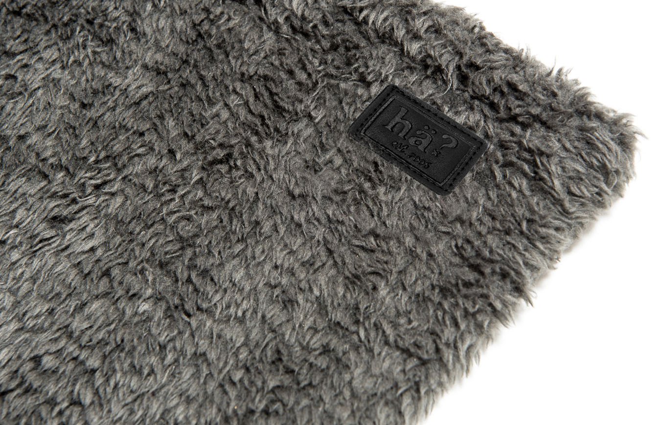 Detailaufnahme eines grauen Wellness Neckwarmers mit flauschigem Polar Fleece und Lederpatch mit Logo.
