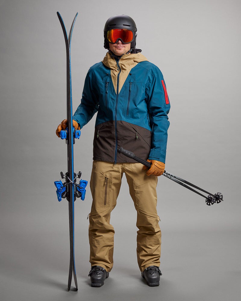 Mann in Skikleidung Mann in Skikleidung mit Ski und Stöcken. Er trägt eine Sand farbende Y-1 HD GORE-TEX Pro 3L Shell Pant.