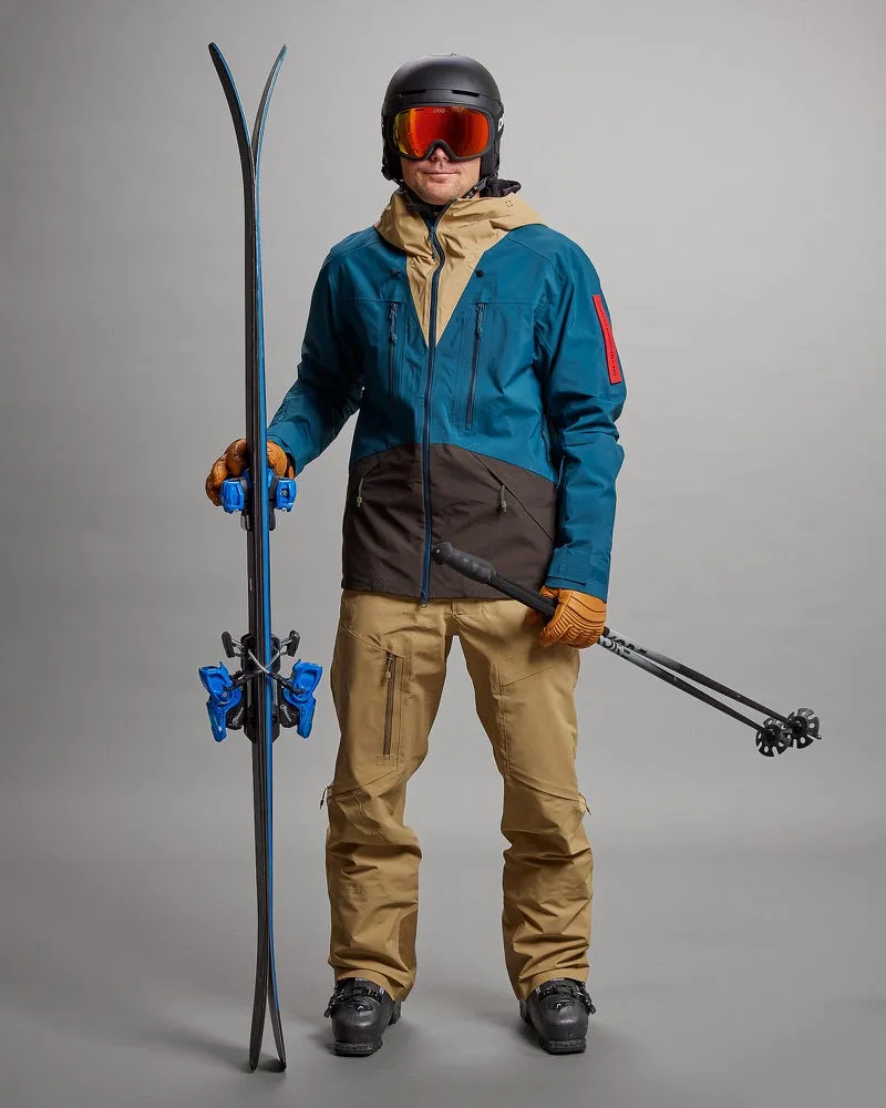 Mann in Skikleidung mit Ski und Stöcken. Er trägt eine Sand farbende Y-1 HD GORE-TEX Pro 3L Shell Pant.
