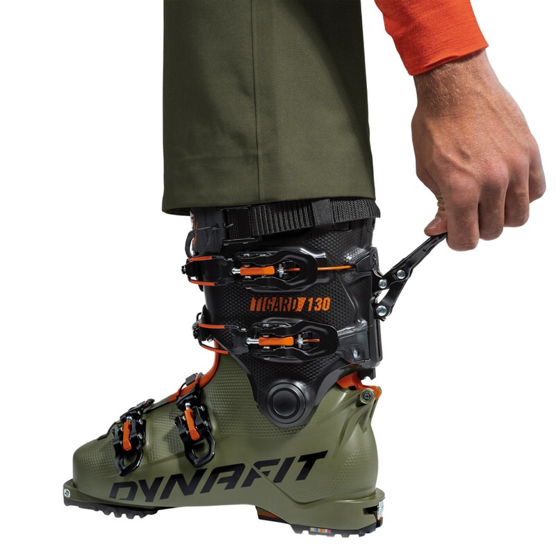 Dynafit Tigard Skischuh Nahaufnahme von einem Dynafit Tigard Alpine Tech Skischuh mit Hand, die den Ski-/Walk-Mechanismus betätigt.