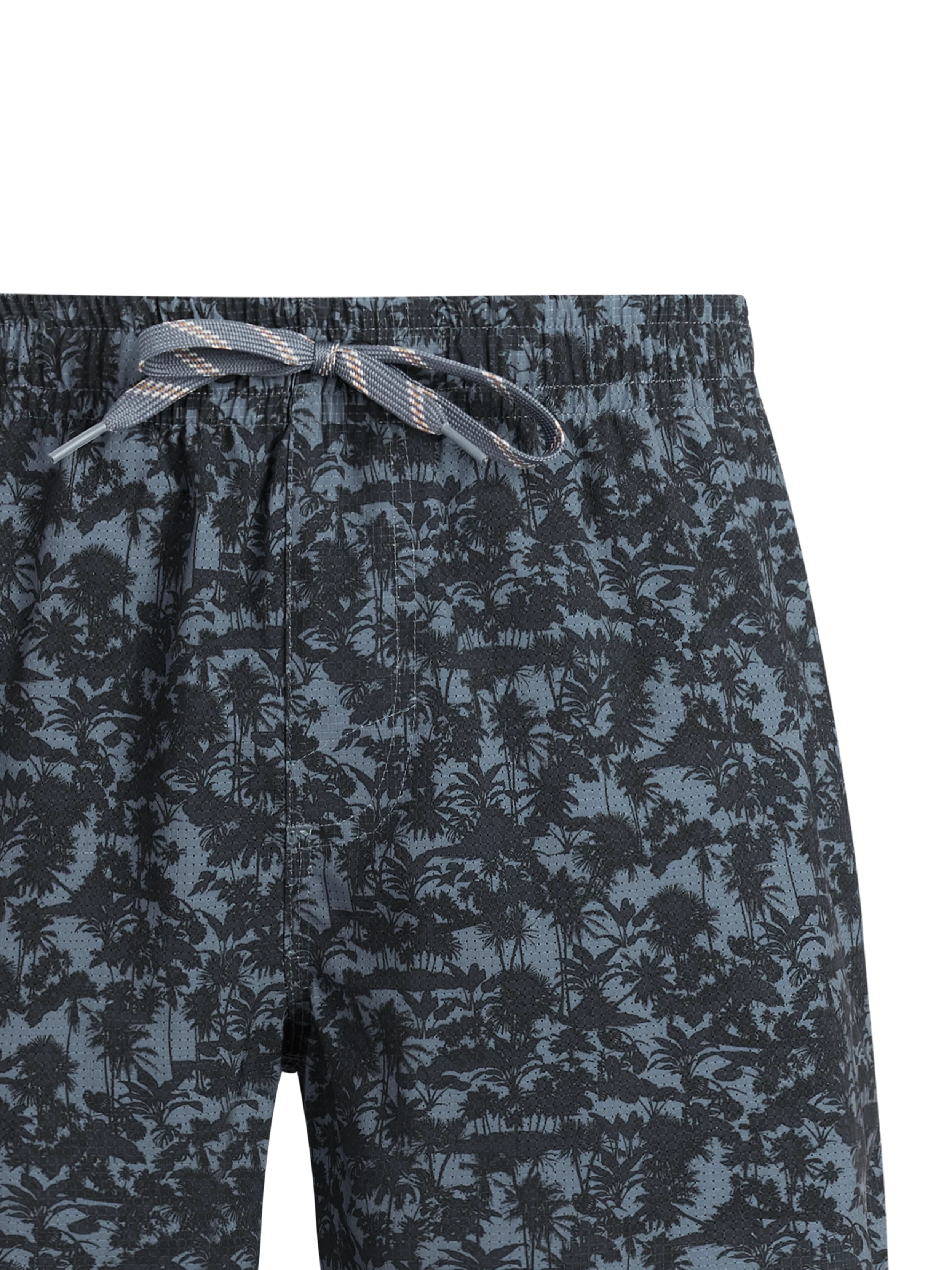 Nahaufnahme einer Shorts mit dunklem Palmenmuster und grau-brauner Kordel am elastischen Bund.
