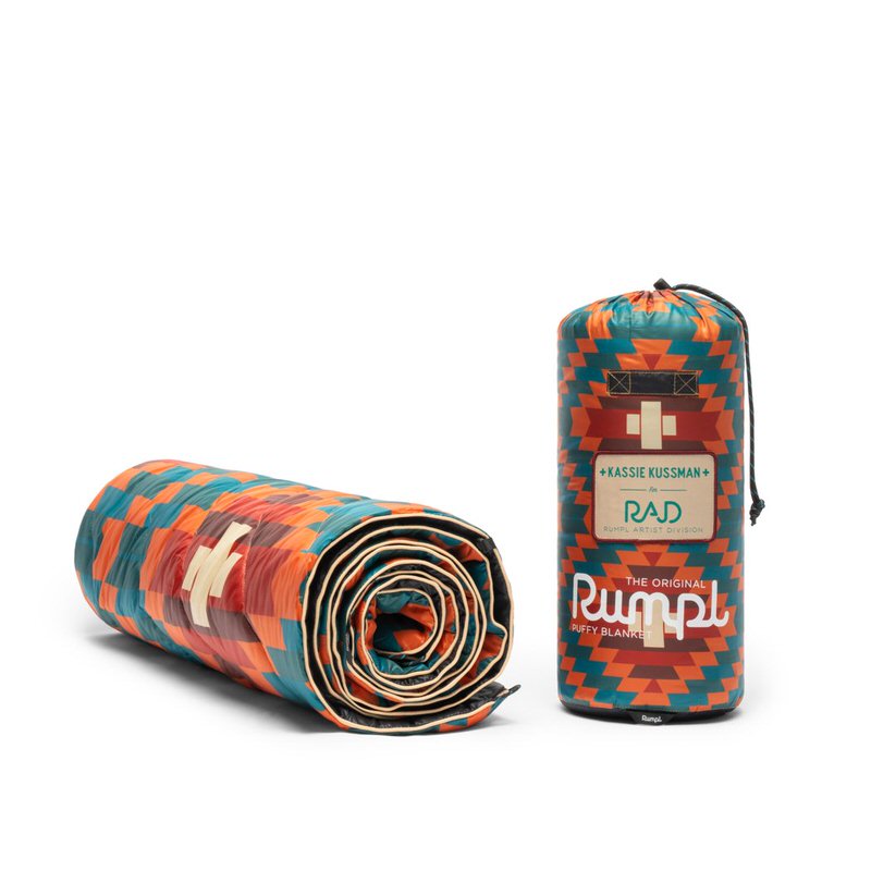 Gerollte Rumpl Puffy Blanket, Copper Basket Muster, neben verpackter Decke mit Logo.