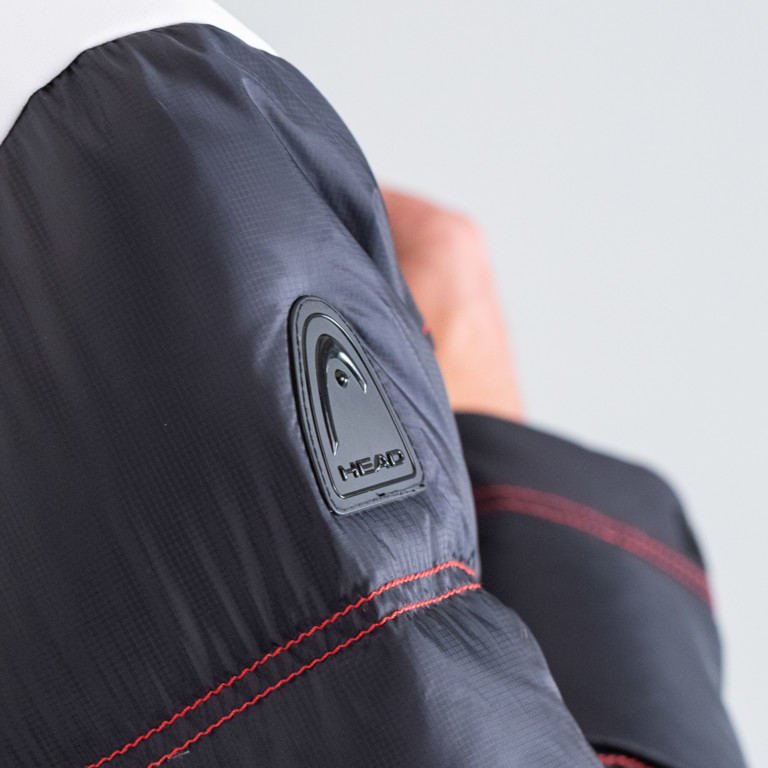 Vue détaillée de la veste de ski Head PORSCHE pour hommes : manches avec logo Head et surpiqûres rouges.