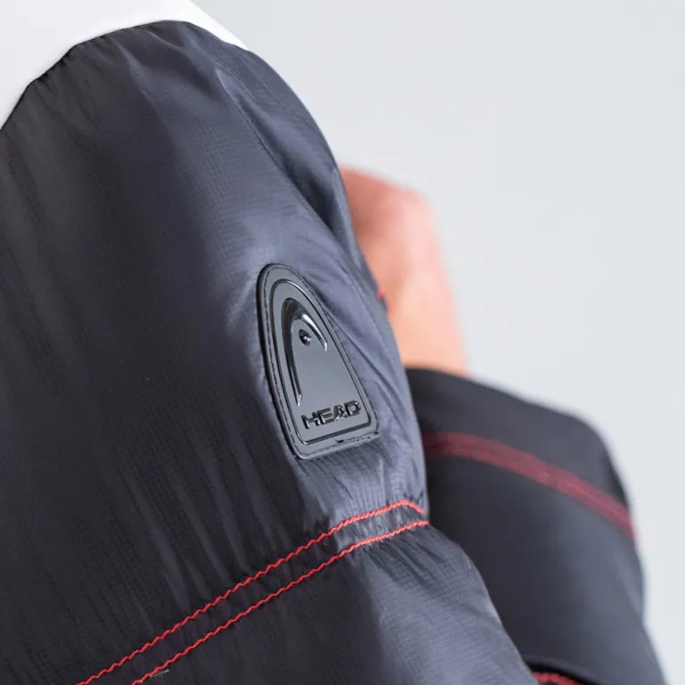 Particolare della giacca da sci Head PORSCHE da uomo: maniche con logo Head e cuciture decorative rosse.