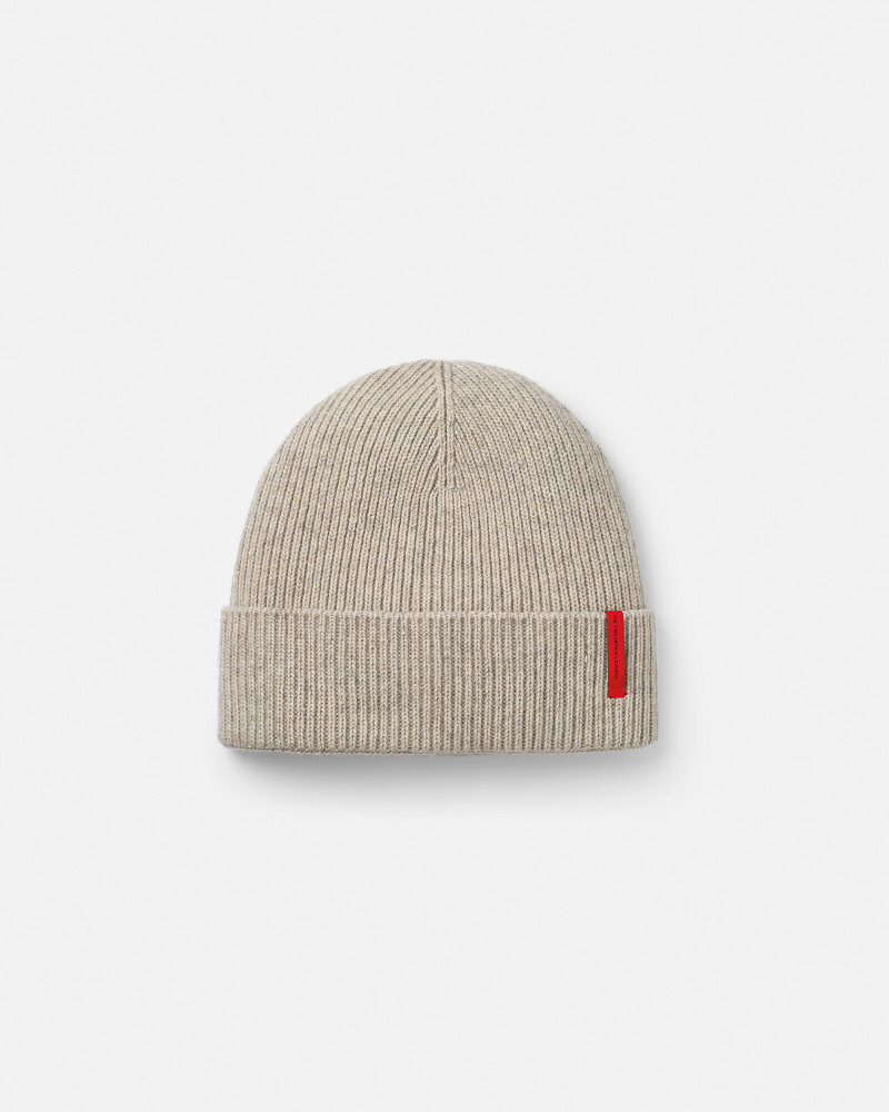 Beige gerippte Cashmere Mix Beanie mit rotem, vertikalem Silikon-Logo auf weißem Hintergrund.