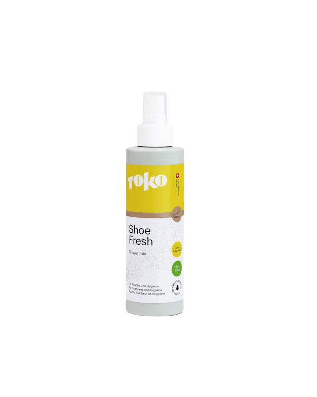 Eine Flasche "Toko Shoe Fresh Flower mix" mit Sprühkopf, gelbem Etikett und grüner Basis, vor einem weißen Hintergrund.