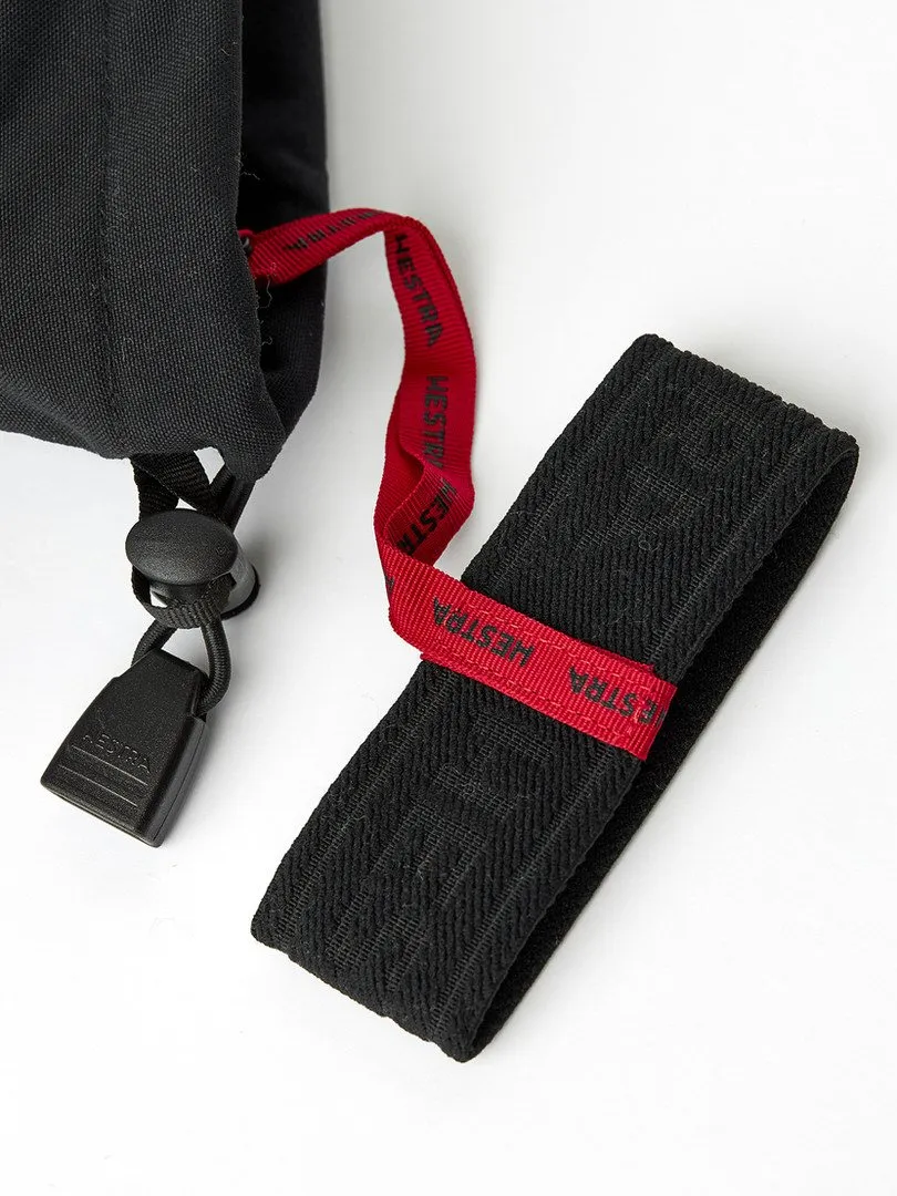 Détail d'un gant noir avec cordon de serrage et ruban, chacun avec un ruban rouge portant l'inscription "HESTRA".
