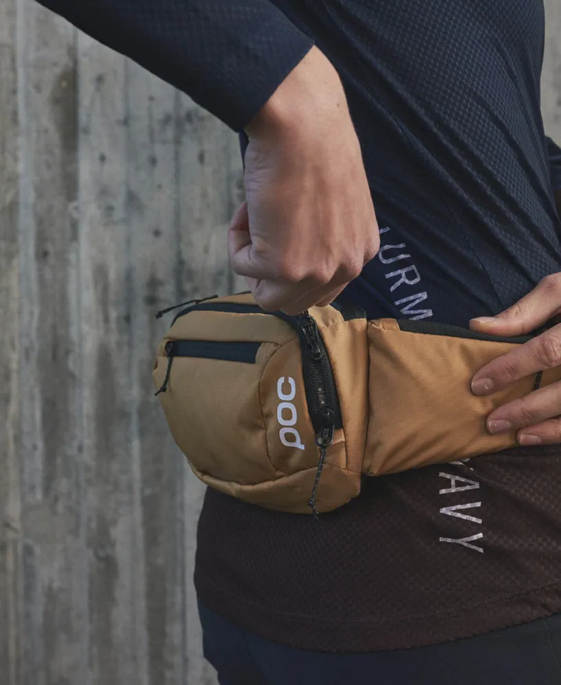 Personne avec sac de hanche POC Lamina en Aragonite Brown. Le sac a des compartiments et des fermetures éclair.