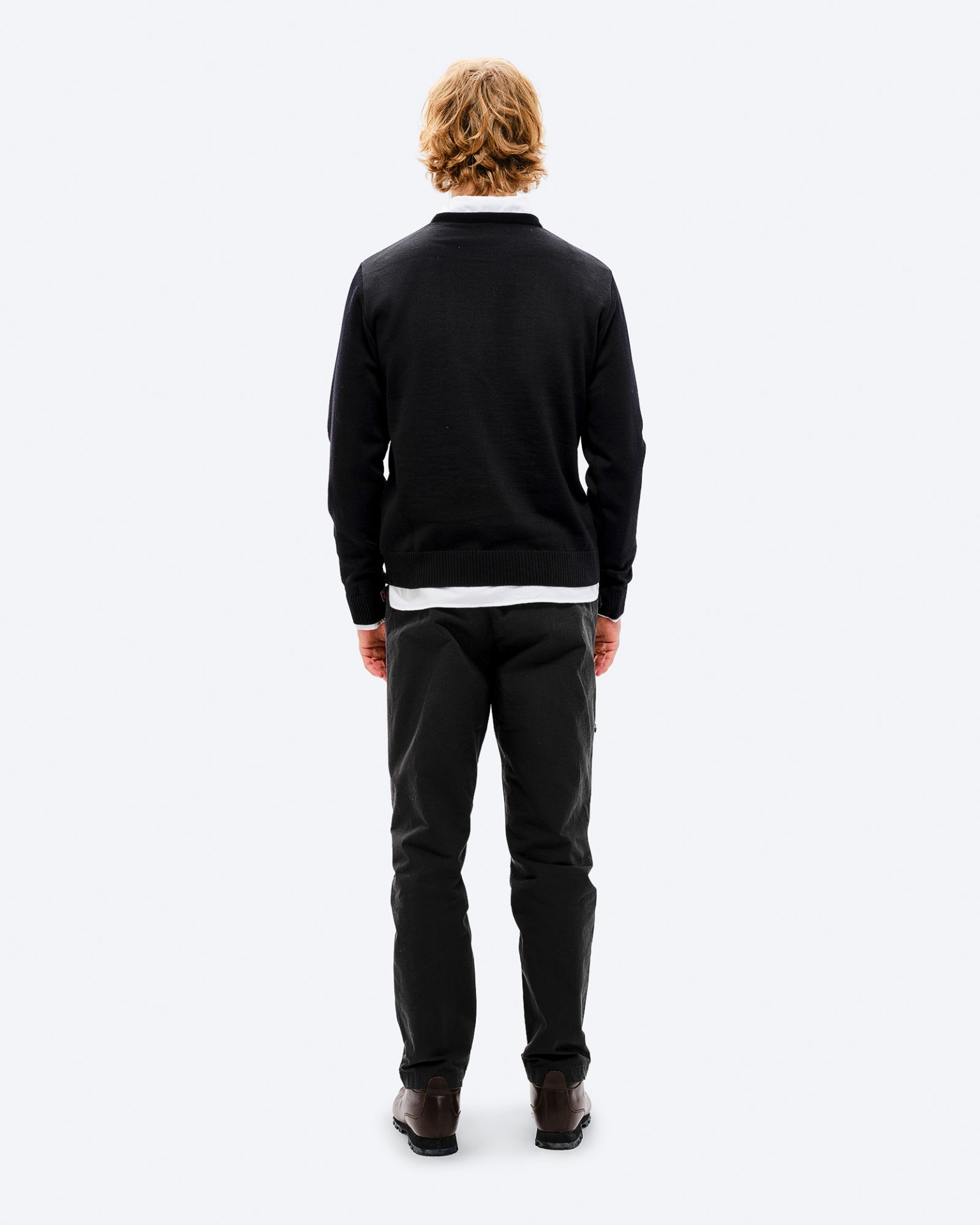 Man in K-3 ski outfit Back view of a man with blond hair wearing a black K-3 ski sweater, pants and shoes against a white background.