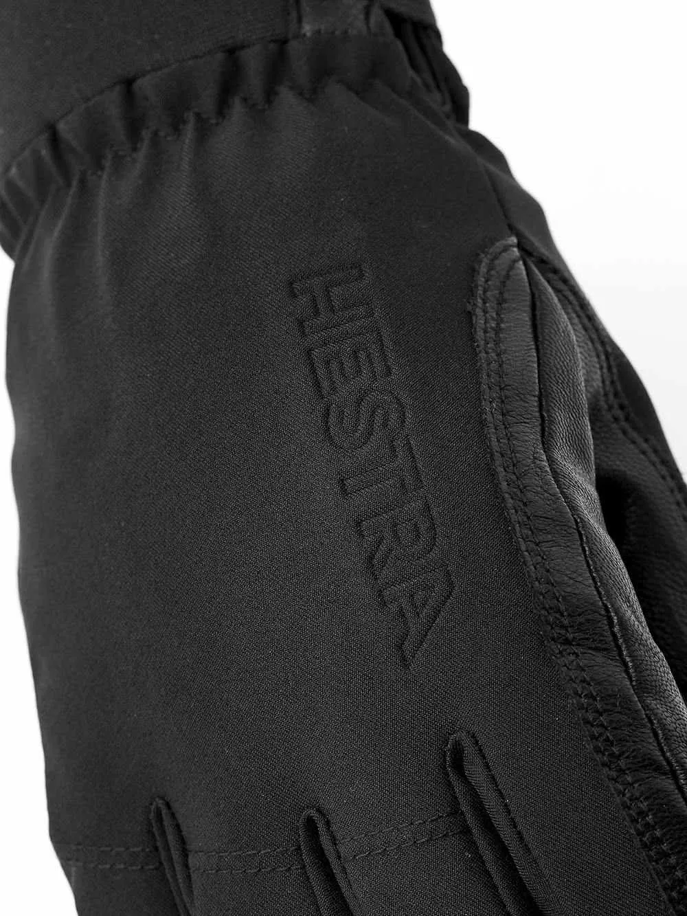 Gros plan sur un gant noir Hestra avec des détails en cuir et le nom de la marque gravé.