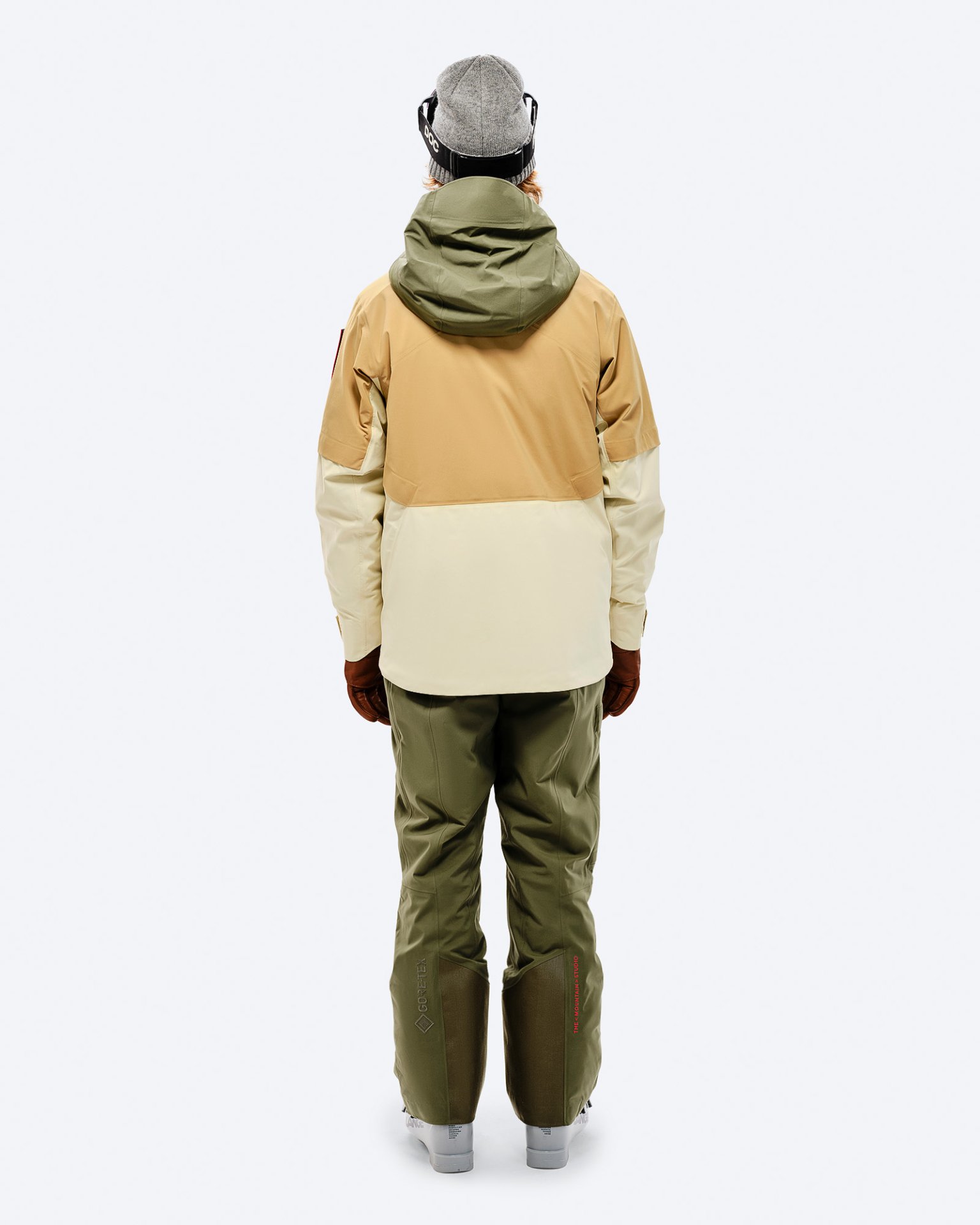 Winterbekleidung Outfit Person von hinten in Winterbekleidung. Gore-Tex P-1 Hose in Winter Moss, beige-braune Jacke mit grüner Kapuze.