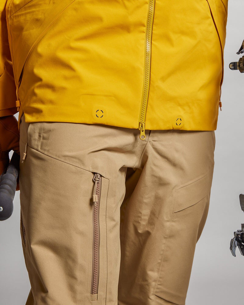 Y-1 HD GORE-TEX Hose Detailaufnahme der Y-1 HD GORE-TEX Pro 3L Shell Pant in Sand, mit Reissverschluss-Tasche und Jacke.
