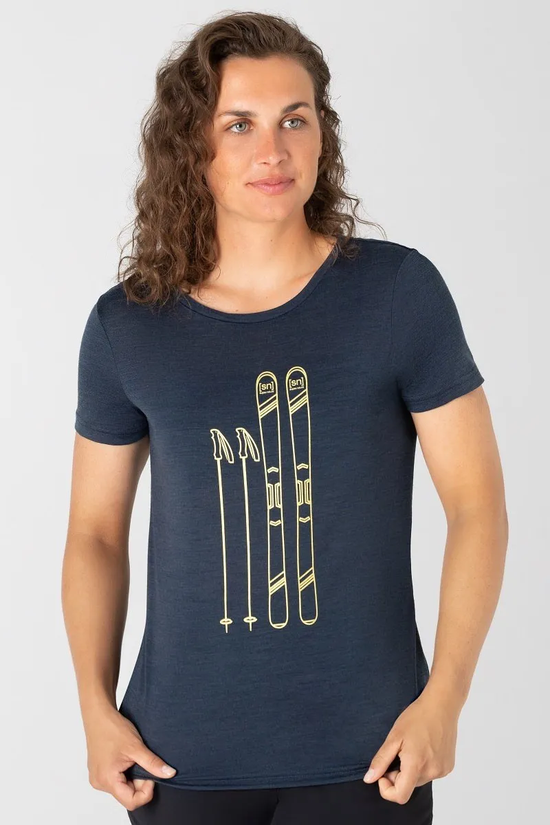 Donna che indossa una t-shirt da sci blu con stampa dorata di sci e bastoni.