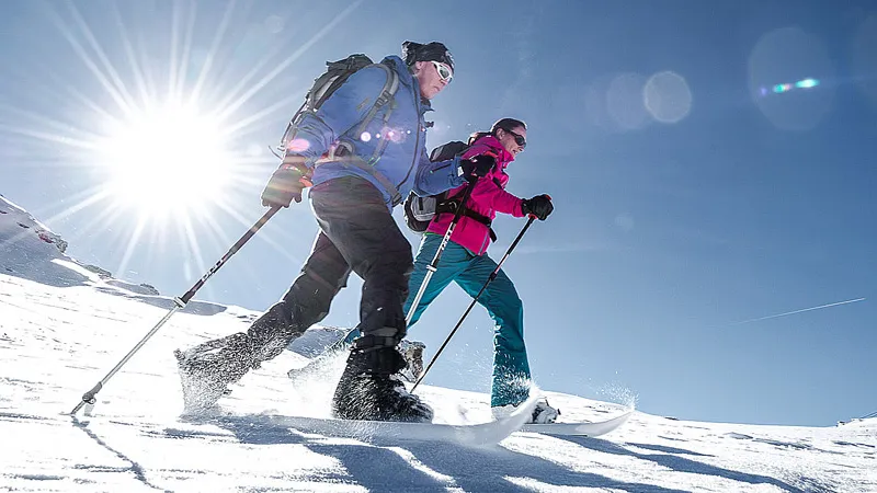 Due persone con Softboot Crossblades, bastoncini e zaini sulla neve.