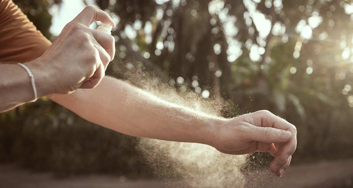 Insektenschutzmittel Anwendung Eine Person sprüht Insektenschutzmittel auf ihren Arm im Freien.