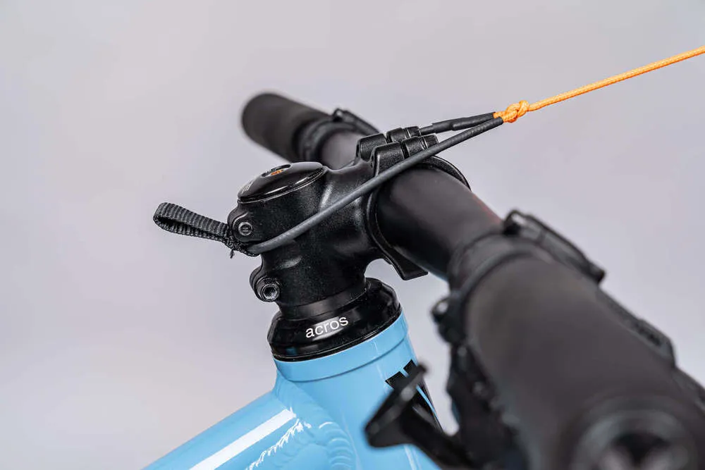 Nahaufnahme eines Fahrradlenkers mit Zugseil, das mit einem Knoten befestigt ist. Das Zugsystem 'kommit' ist montiert.