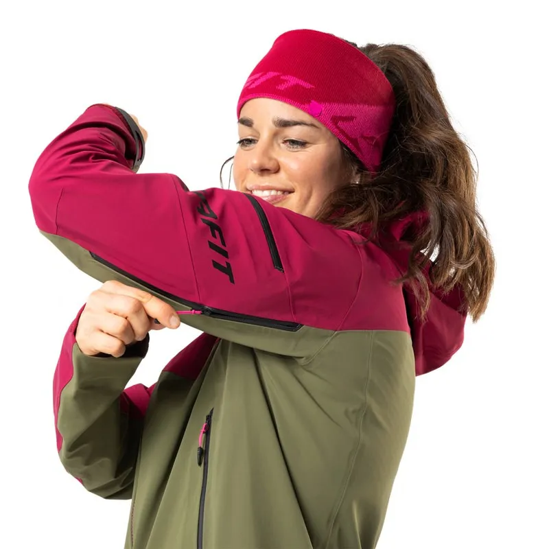 Frau mit Stirnband und Beast Hybrid Women Jacket in Beet Red, öffnet den Ärmelreißverschluss.