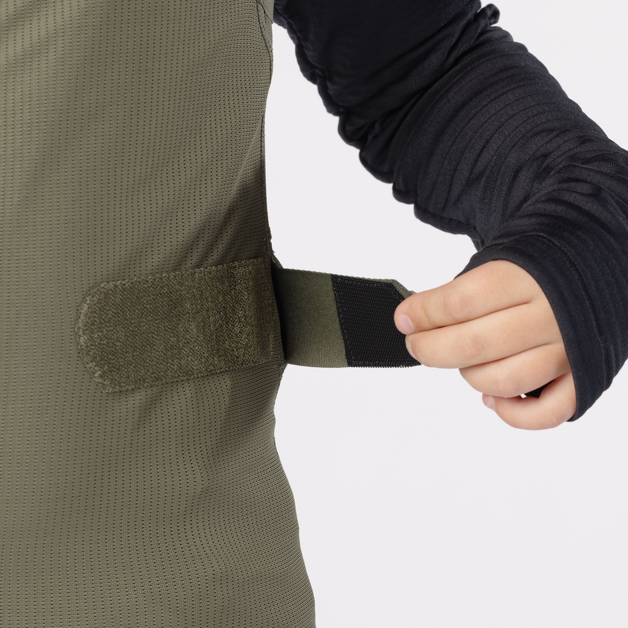 Gilet junior verde Gilet junior verde con chiusura a velcro in vita, indossato su un top nero a maniche lunghe.