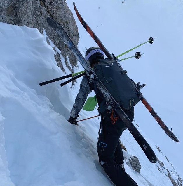 Personne avec un sac à dos Salewa Randonee et des skis sur le dos, lors d'une montée dans la neige.